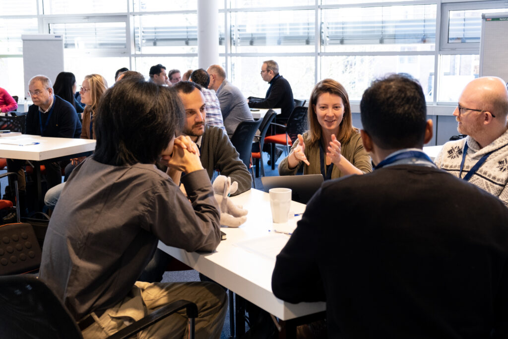 Photo of session attendees, sitting around a table, engaged in a discussion 